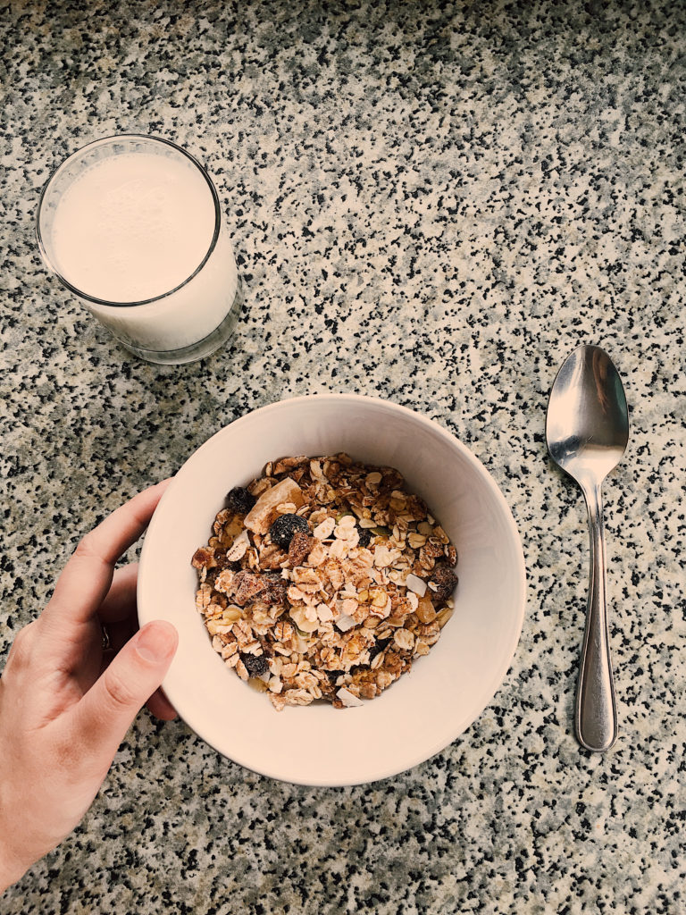 bowl of muesli and glass of milk against granite countertop