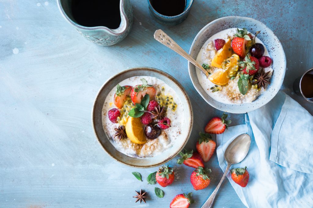 bowls of oatmeal with tropical fruit and berries on a white background