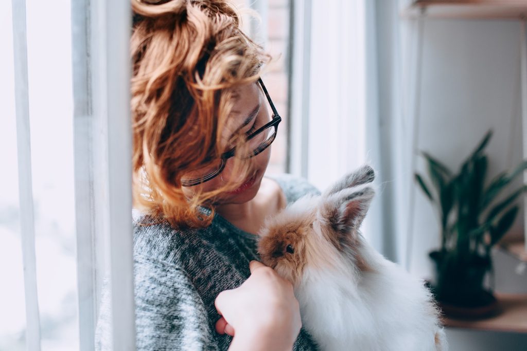 caring for your exotic pet, woman holding rabbit near window